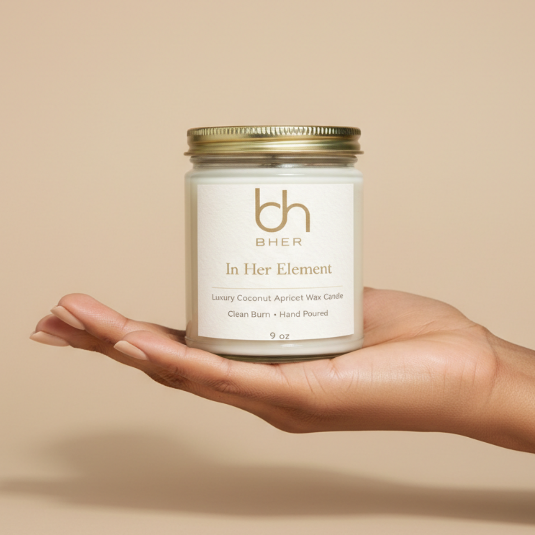 Candle jar labeled 'In Her Element' held in a hand against a beige background