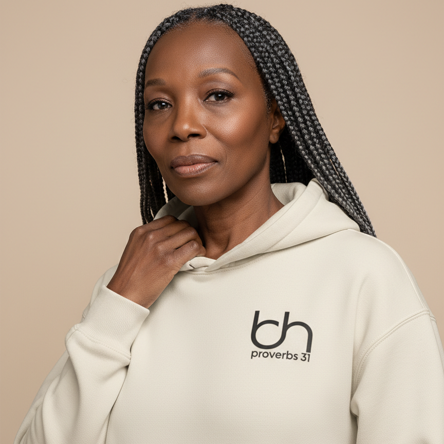 Woman wearing a beige BH Proverbs 31 hoodie against a neutral background.