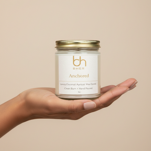 B.HER Anchored luxury coconut apricot wax candle held in hand against a soft beige background