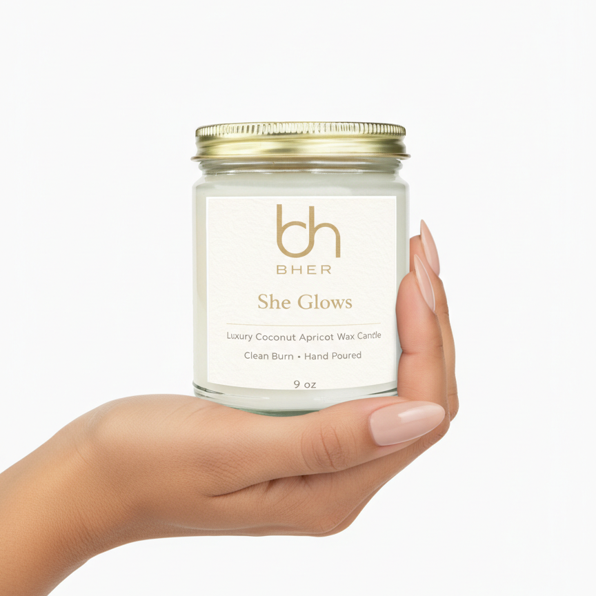 Hand holding B.HER She Glows luxury coconut apricot wax candle on a white background